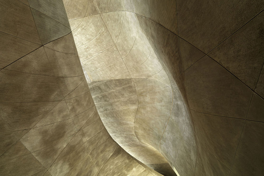 Abstract close-up of curving beige architectural surfaces with light and shadow creating flowing patterns