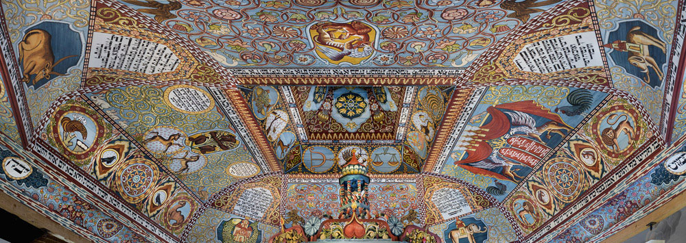 Ornately painted ceiling with colorful folk-art designs, animals, zodiac symbols, and decorative script panels
